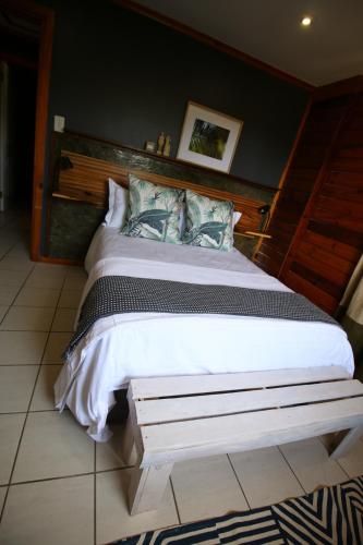 a bedroom with a large bed with a wooden headboard at The Wild Edge First Light Cottage in Knysna