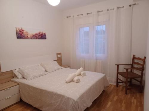 um quarto com uma cama com lençóis brancos e uma cadeira em Reformado, cómodo y funcional en Medina del Campo em Medina del Campo