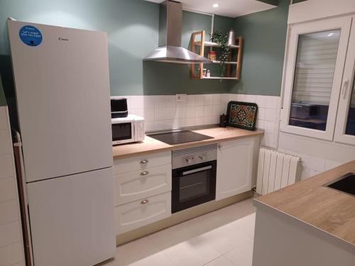 uma cozinha com electrodomésticos brancos e um frigorífico branco em Reformado, cómodo y funcional en Medina del Campo em Medina del Campo