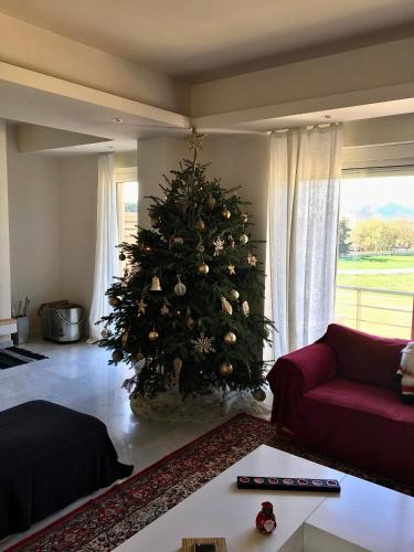 a christmas tree in a living room with a red couch at Legrena Beach Villa in Sounio