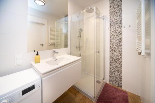ein weißes Bad mit einem Waschbecken und einer Dusche in der Unterkunft Maya's Flats & Resorts 43 -Swietej Babary in Danzig