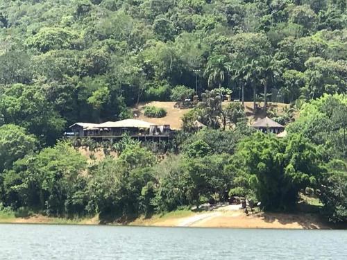 a house on a hill next to a body of water at Villa Pantai Secret Place in Miracatu