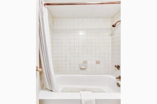 y baño con bañera y azulejos blancos. en Quality Inn Nacogdoches Near University, en Nacogdoches