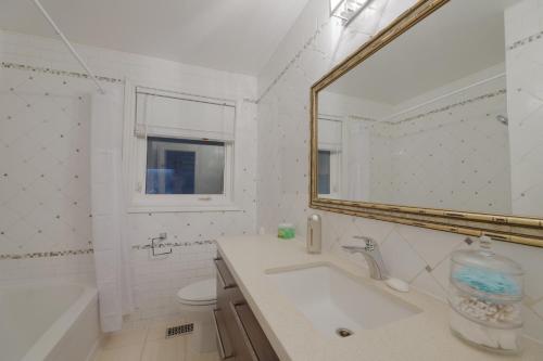 Baño blanco con lavabo y espejo en Master Accord With Bath & Steps to Subway, en Toronto