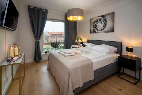 1 dormitorio con 1 cama con sábanas blancas y ventana en Maya's Flats & Resorts - River View, en Gdansk