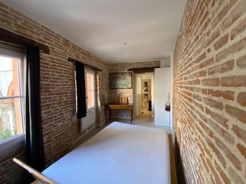 a room with a brick wall and a bed in it at Capitole - Appartement Standing au coeur du Centre in Toulouse