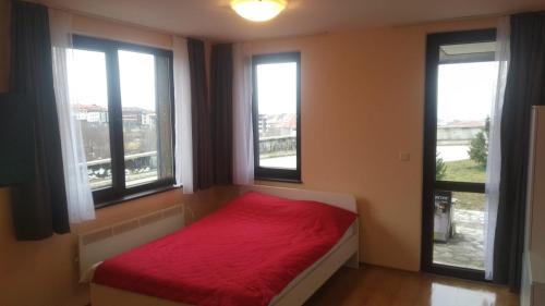 バンスコにあるRoyal Park Spa Bansko, private apartments within the complexのベッドルーム1室(赤いベッド1台、窓3つ付)
