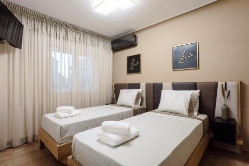 a bedroom with two beds with white sheets at Volos luxury maisonette-Pelion view in Volos