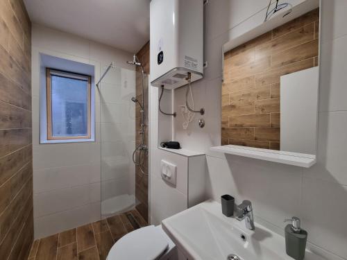 a white bathroom with a toilet and a sink at Nivalis Hill N&V in Jahorina