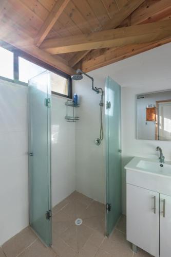 a bathroom with a glass shower and a sink at שיר החורש in Shomera