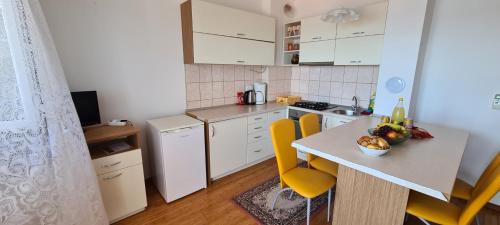 eine kleine Küche mit einem Tisch und gelben Stühlen in der Unterkunft Apartmani Gizela in Trogir