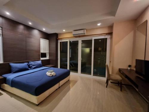 sypialnia z niebieskim łóżkiem i telewizorem w obiekcie Tinker Bell Pool Villa w mieście Jomtien Beach