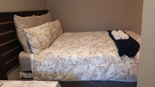 a bed with a black and white comforter and pillows at Budget self-contained room in Pretoria