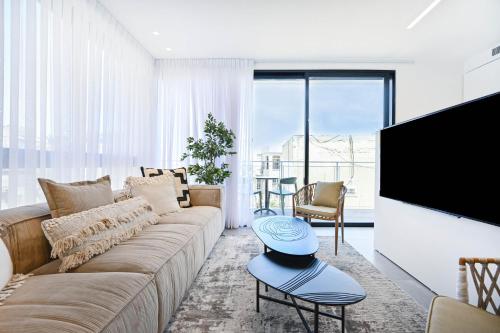 a living room with a couch and a flat screen tv at Sweet Home by HolyGuest in Tel Aviv