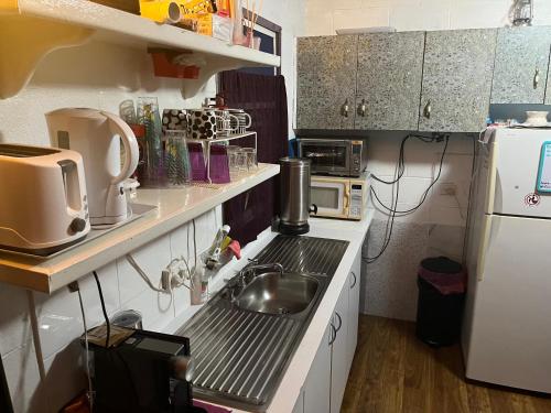 a small kitchen with a sink and a refrigerator at The downstairs delight 2brm , 6+ guests & dogs ok in Lake Munmorah