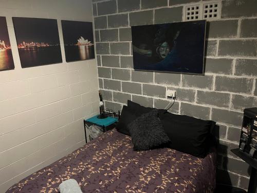 a bedroom with a bed and a brick wall at The downstairs delight 2brm , 6+ guests & dogs ok in Lake Munmorah