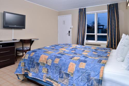 a bedroom with a bed and a desk and a television at Canadas Best Value Inn St. Catharines in St. Catharines