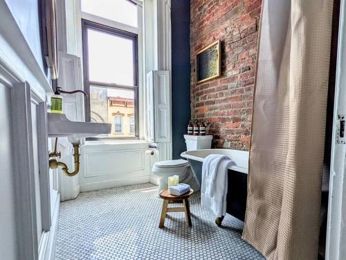 HostWise Stays - Industrial Vintage Style, Minutes to Downtown في بيتسبرغ: حمام بجدار من الطوب وحوض استحمام