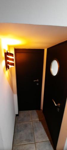 a hallway with two black doors and a tile floor at Nez sur la croisette. in Dinant