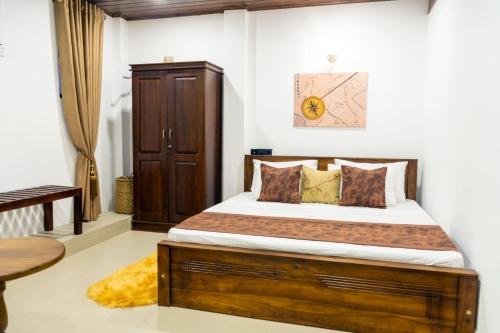 Cinnamon Tan Boutique Hotel في نيجومبو: غرفة نوم بسرير كبير مع اطار خشبي