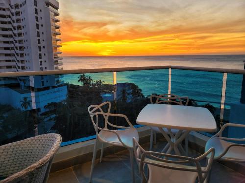 a balcony with a table and chairs and a sunset at RESERVA DEL MAR - Playa Salguero - By INMOBILIARIA VS in Santa Marta