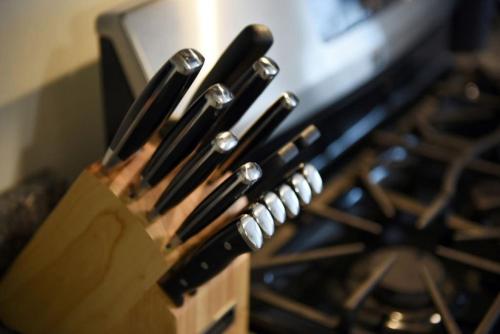 a group of knives in a wooden holder next to an oven at HostWise Stays - Butler St, Lower Lawrenceville, Brand New! in Pittsburgh