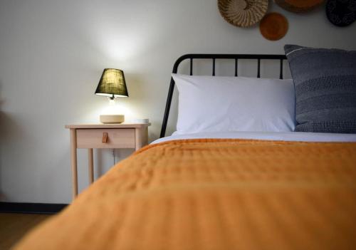 a bed with an orange blanket and a table with a lamp at HostWise Stays - Butler St, Lower Lawrenceville, Brand New! in Pittsburgh