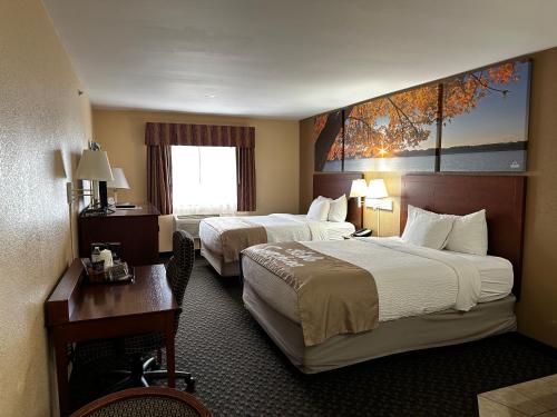a hotel room with two beds and a table and a desk at Days Inn by Wyndham Imlay City in Imlay City