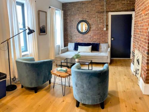 a living room with two chairs and a brick wall at HostWise Stays - The Ohioan - Beautiful Brick Apt, Minutes to Downtown! in Pittsburgh