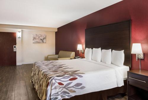 um quarto de hotel com uma cama grande e uma cadeira em Red Roof Inn Tupelo em Tupelo