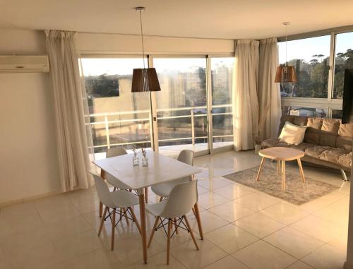 uma sala de estar com uma mesa e cadeiras e um sofá em Blaumer Apartamentos - Edificio Aguila Dorada em Punta del Este