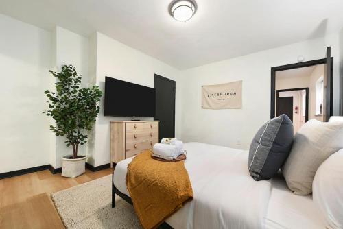 a bedroom with a white bed and a flat screen tv at HostWise Stays - Pet Friendly Butler St Apt, Ground Floor with Private Entrance in Pittsburgh
