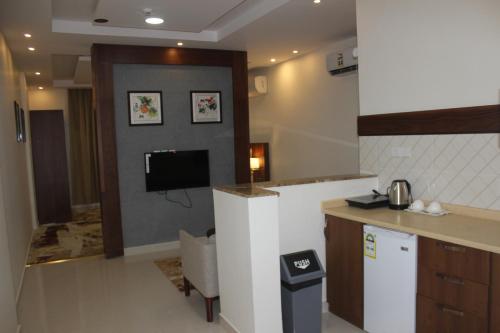 a kitchen with a counter and a tv in a room at Delta Hotel Suites in Jazan