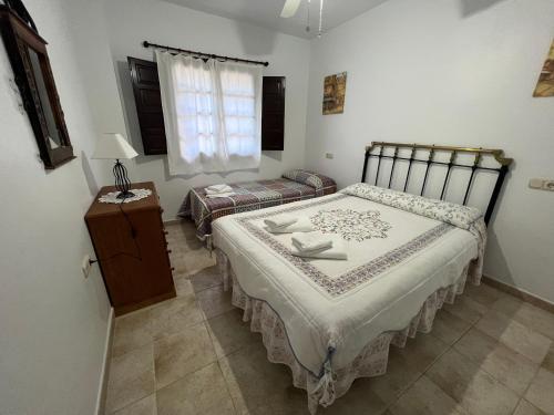 1 Schlafzimmer mit 2 Betten, einem Tisch und einem Fenster in der Unterkunft Casa Lirios in Jimera de Líbar
