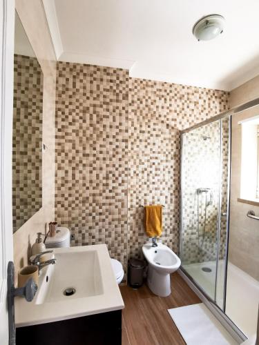 a bathroom with a sink and a toilet and a shower at Casas dos Avós in Nazaré