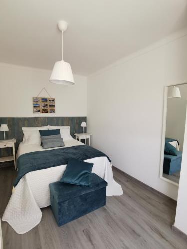 a white bedroom with a large bed and a mirror at Casas dos Avós in Nazaré
