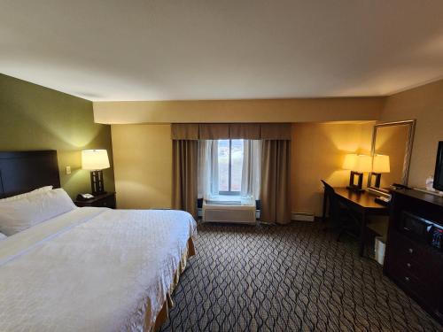 a hotel room with a bed and a desk and a window at Wingate by Wyndham Kittanning in Kittanning