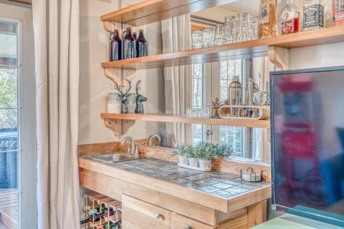 a kitchen with a sink and shelves with bottles at Boho Retreat w/King Bed on Bow River Pathway in Calgary