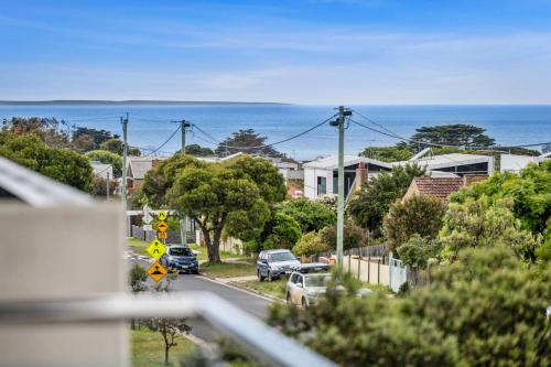 a street with cars parked on the road and the ocean at Boston Central 32a in Torquay