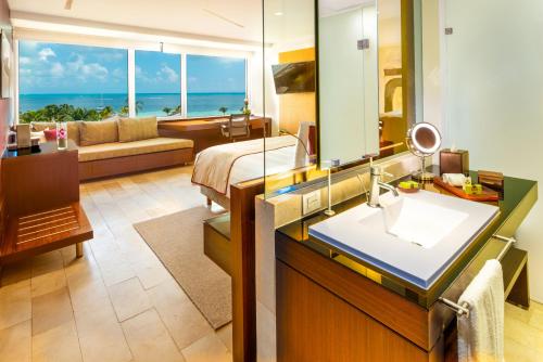 y baño con cama, lavabo y espejo. en InterContinental Presidente Cancun Resort, en Cancún