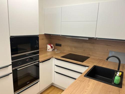 a kitchen with white cabinets and a black sink at Apartman Holesovice,balkon,garaz in Prague