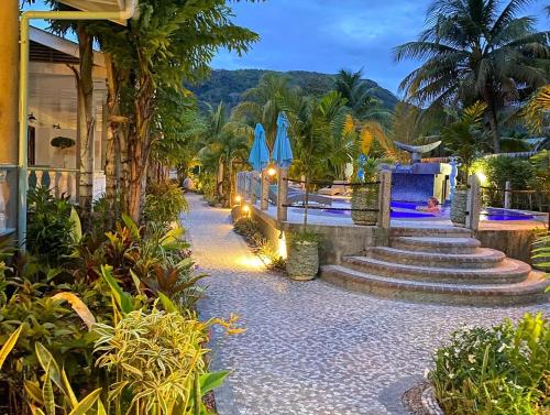 a resort with stairs and blue umbrellas and palm trees at Cabanes Des Anges in La Digue