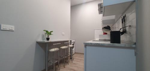 a kitchen with white walls and a counter with stools at Apartamentos Las trece llaves Jacuzzi bajo reserva in Merida