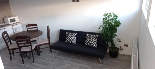 a dining room with a black couch and a table at Cabañas cristal y pascal in Punta Arenas