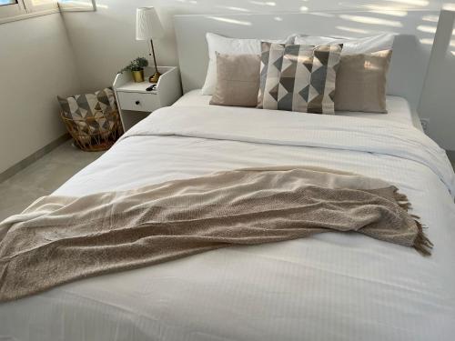 a blanket is laying on a bed in a bedroom at Lux & Comfy ~ Pool ~ Queen Beds in Rishon LeẔiyyon