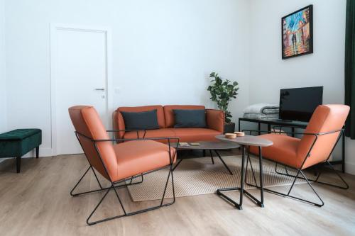 sala de estar con sillas naranjas, mesa y sofá en Apartment The City, en Gante