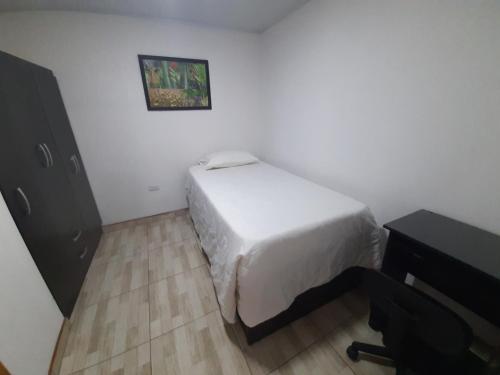 ein kleines Schlafzimmer mit einem Bett und einem Schreibtisch in der Unterkunft Acogedora casa cerca al centro in Manizales
