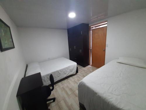 1 Schlafzimmer mit 2 Betten, einem Schreibtisch und einem Fenster in der Unterkunft Acogedora casa cerca al centro in Manizales