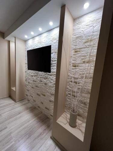 a living room with a stone wall with a tv at ESSE Apartament in Gulbene