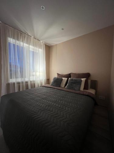 a bedroom with a large bed with a window at ESSE Apartament in Gulbene